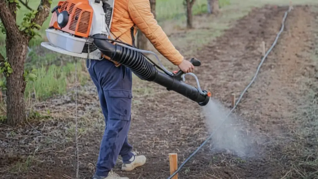 Man operating a NEWTOP motorized backpack sprayer in an orchard.