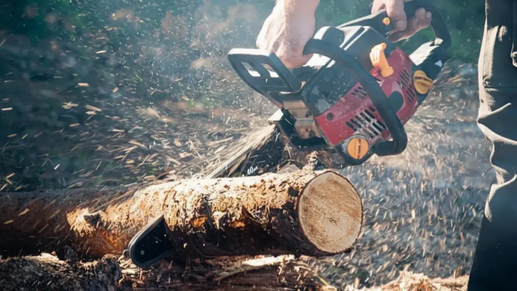 _handheld chainsaw to cut through a log outdoors