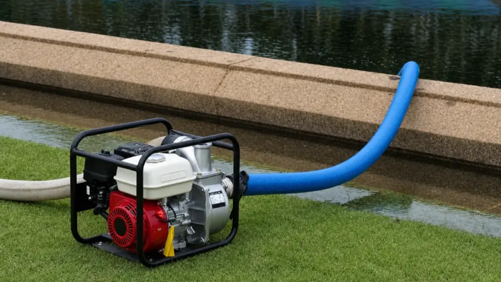 Portable water pump on grass with blue discharge hose