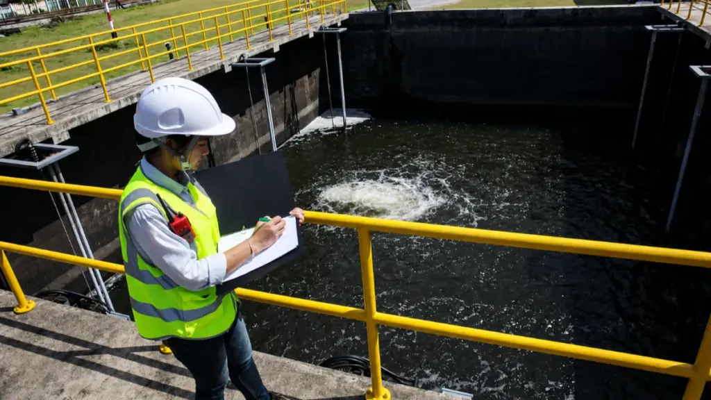 Technician inspecting wastewater tank near water pump system