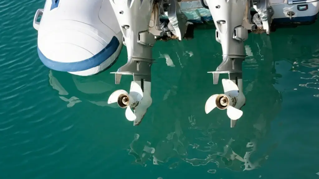 Two outboard boat motors with propellers over clear turquoise water