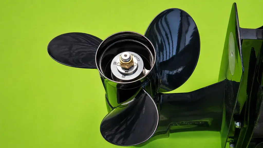 Black outboard propeller close-up against bright green painted hull