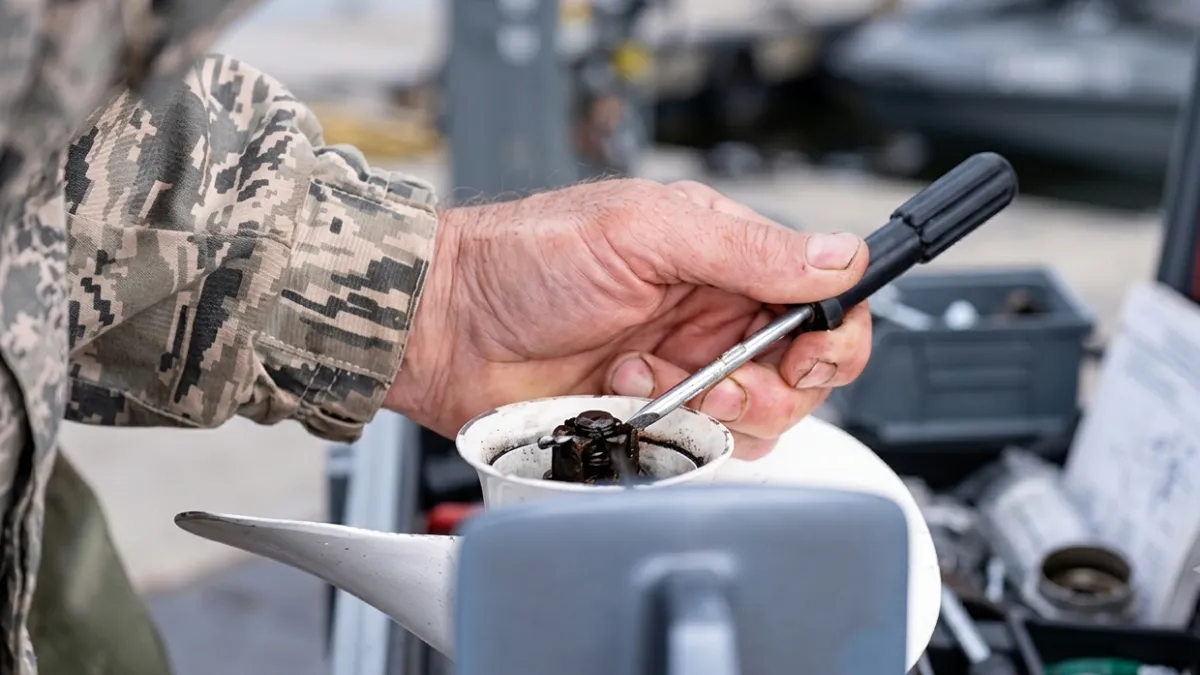 Close-up of a soldier repairing a boat propeller with a screwdriver