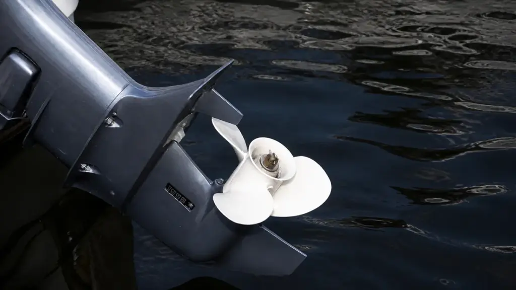 Gray outboard motor with white propeller above calm water