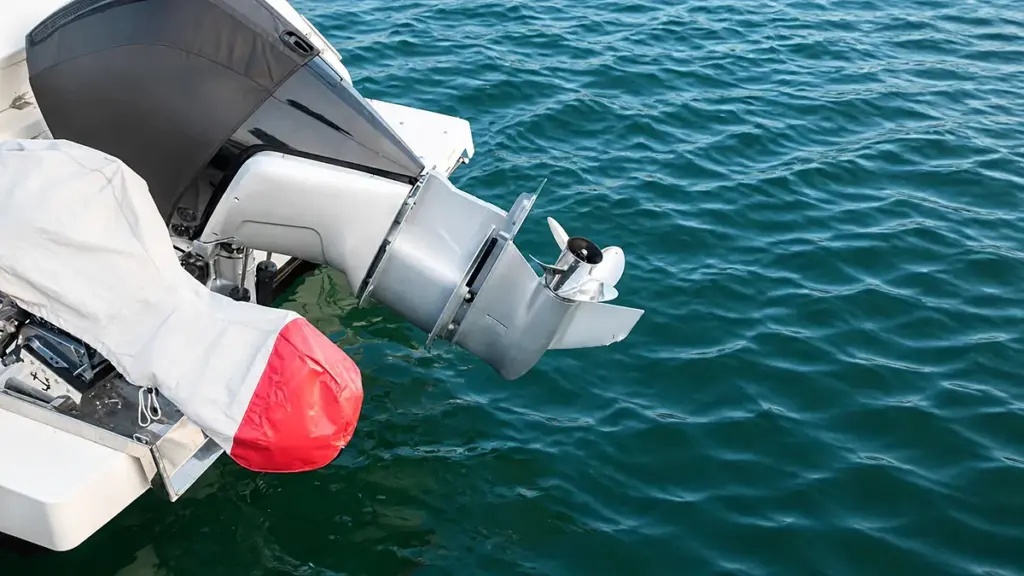 Gray outboard motor with white propeller above rippling blue-green water