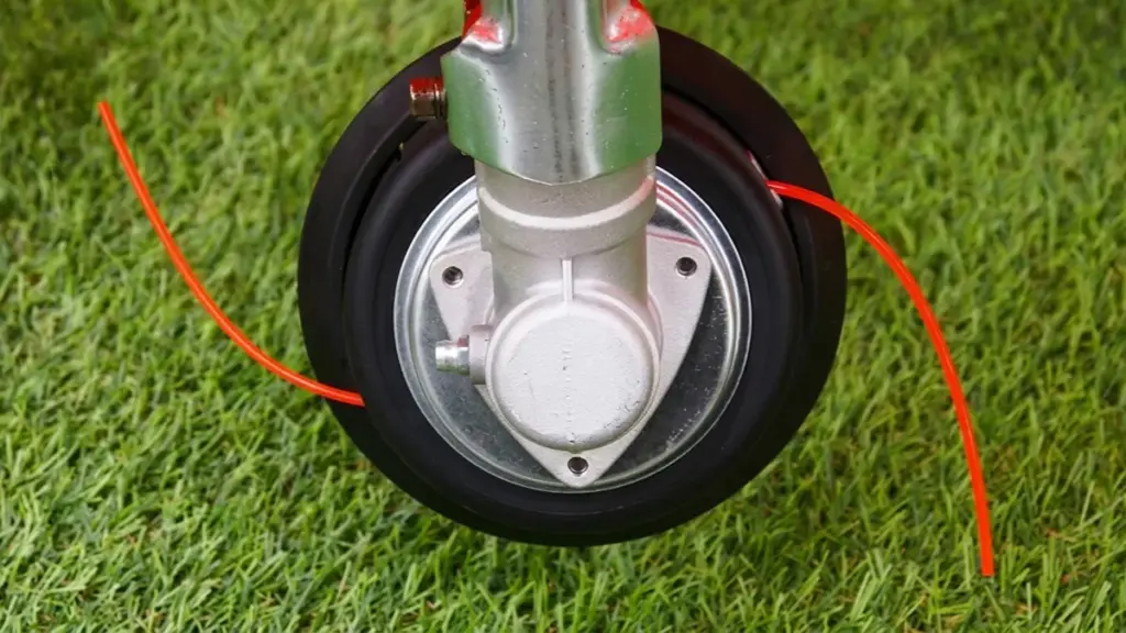 Close-up view of string trimmer gear head on grass