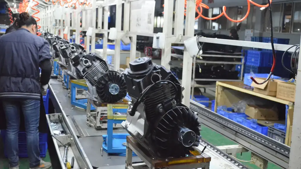 Factory worker assembling small engines along a conveyor belt production line