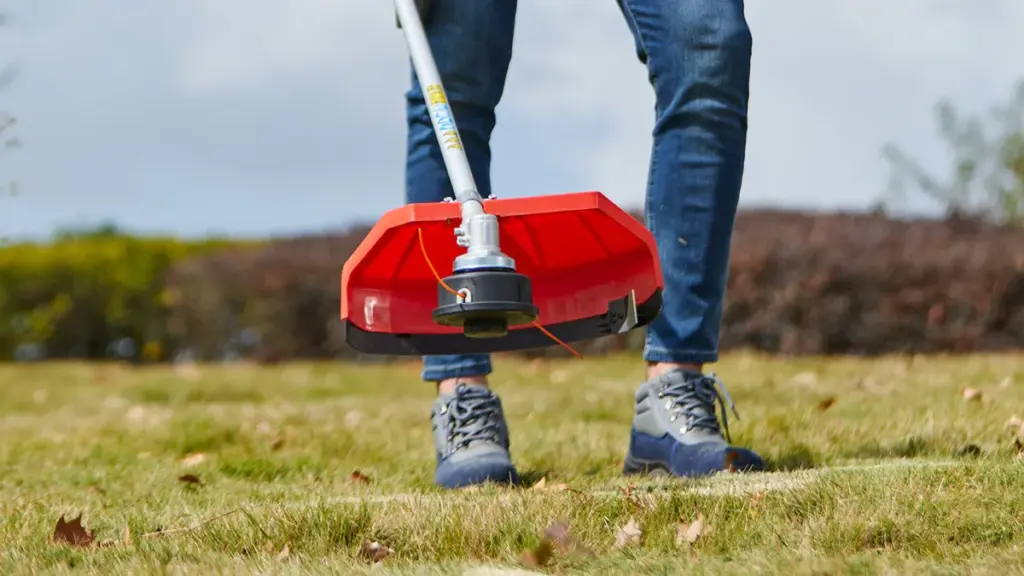 Person operating a string trimmer on a grassy lawn outdoors