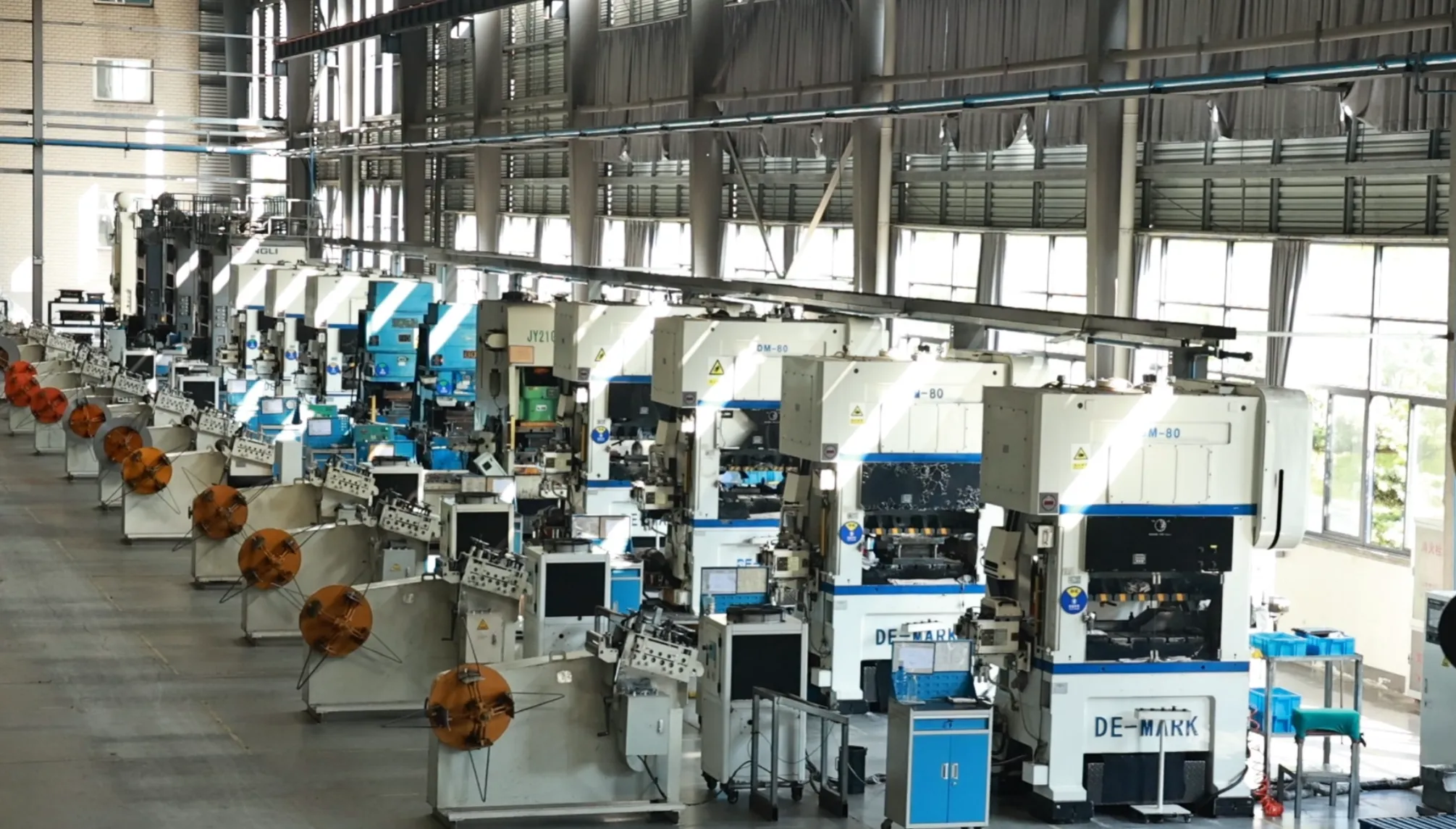 Interior of a stamping workshop featuring rows of large mechanical press machines and metal coiling systems.