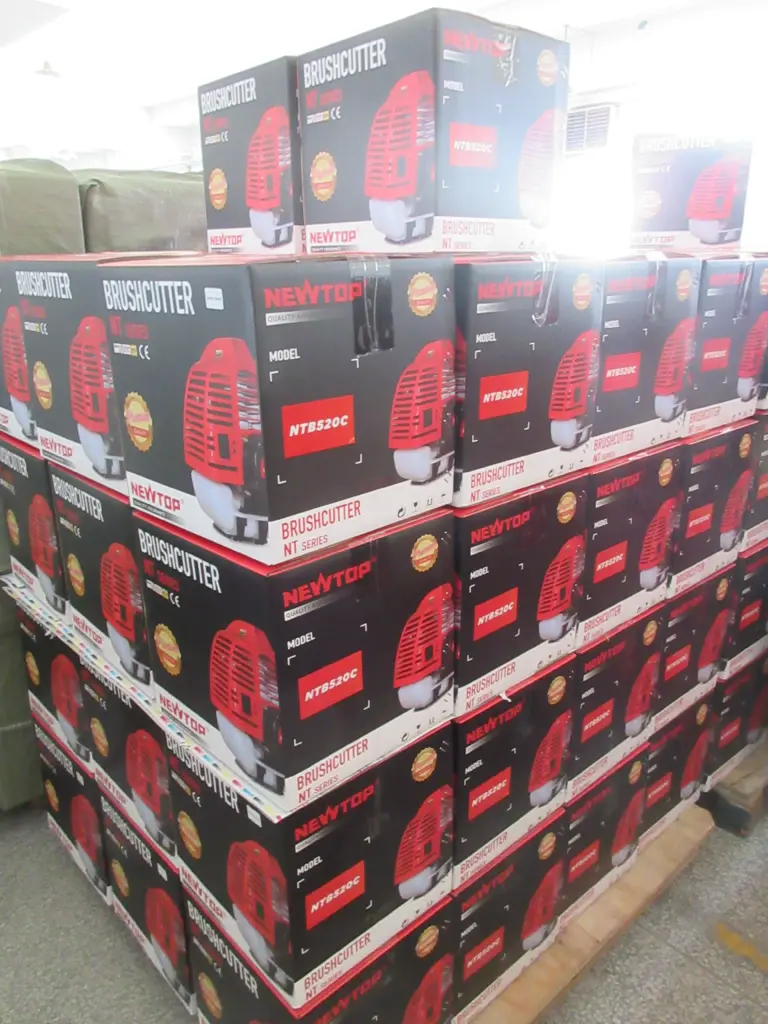 Stacked boxes of New Top NT520C gas brushcutters on a wooden pallet