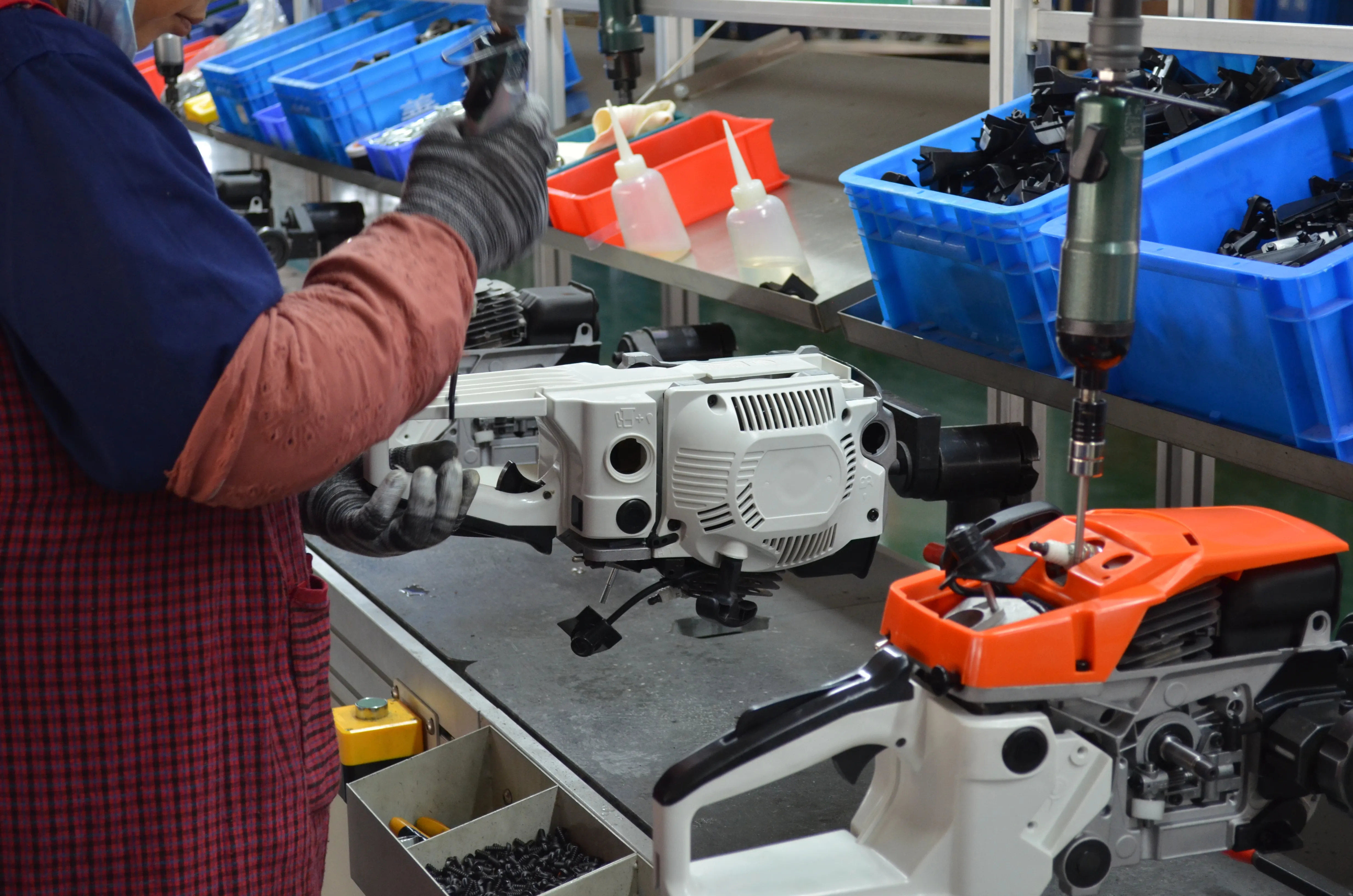 Worker assembling a chainsaw engine on the factory production line