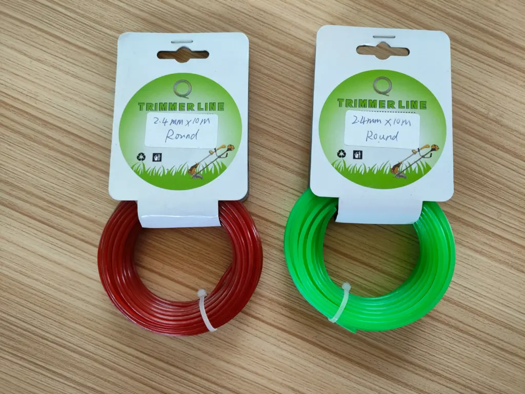 Two spools of round trimmer line, red and green, labeled 2.4mm x 10m on a wooden table